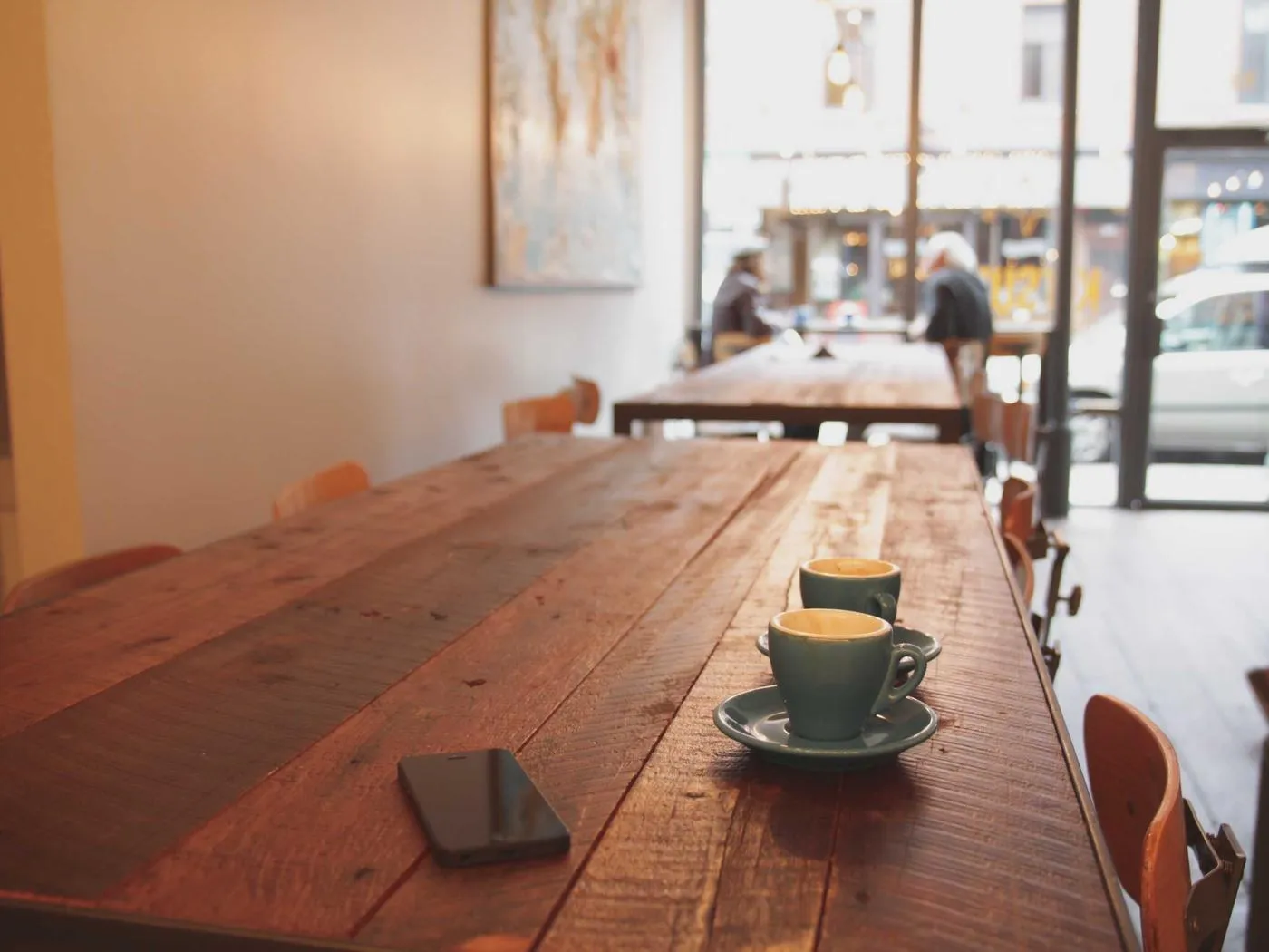 A long wooden communal table in a quiet cafe